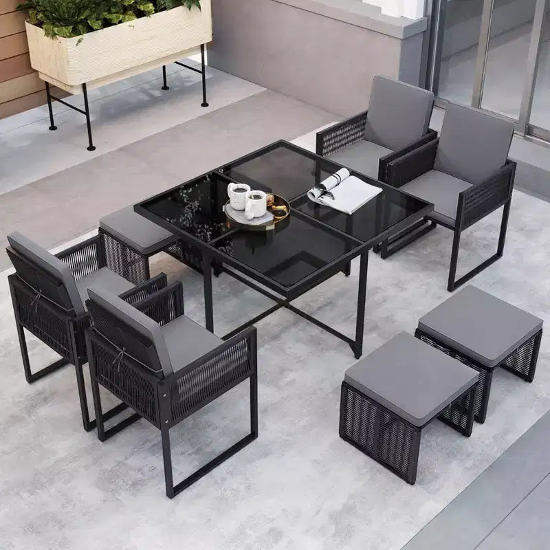 Set da pranzo da patio Costway da 9 pezzi con sedie in rattan PE, tavolo in vetro temperato e pouf